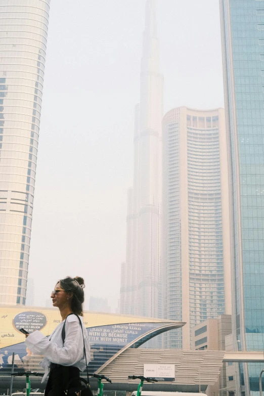 a woman walking down the sidewalk near large buildings