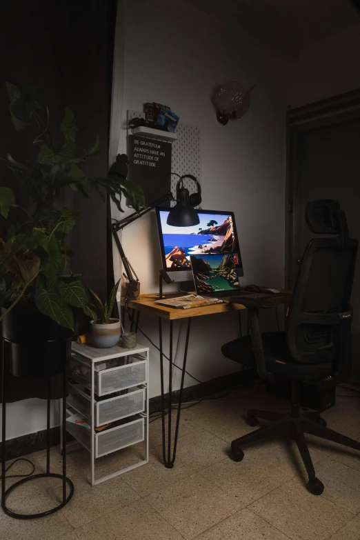 a desk with a keyboard, monitor and a plant