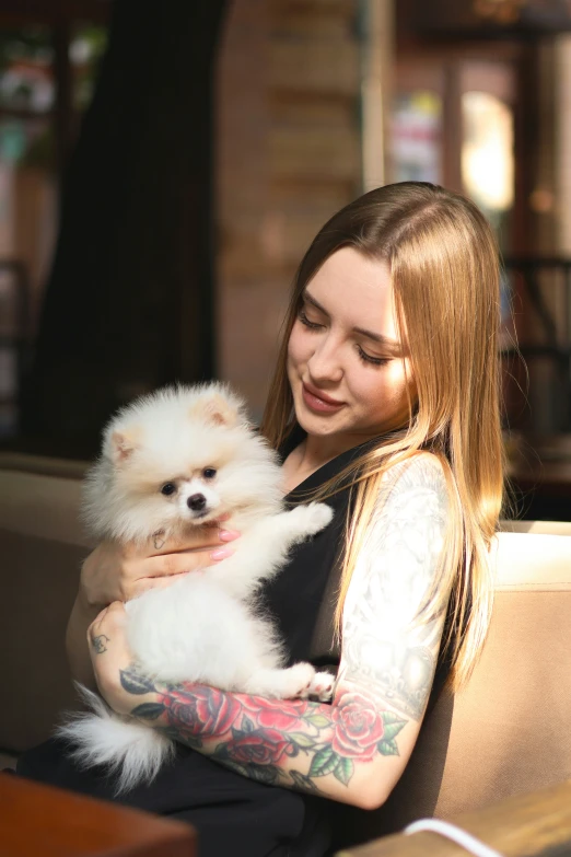 the woman with tattoos is holding a white dog