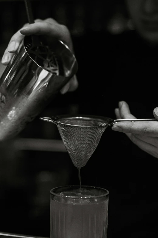 a person mixing some liquid into a cocktail