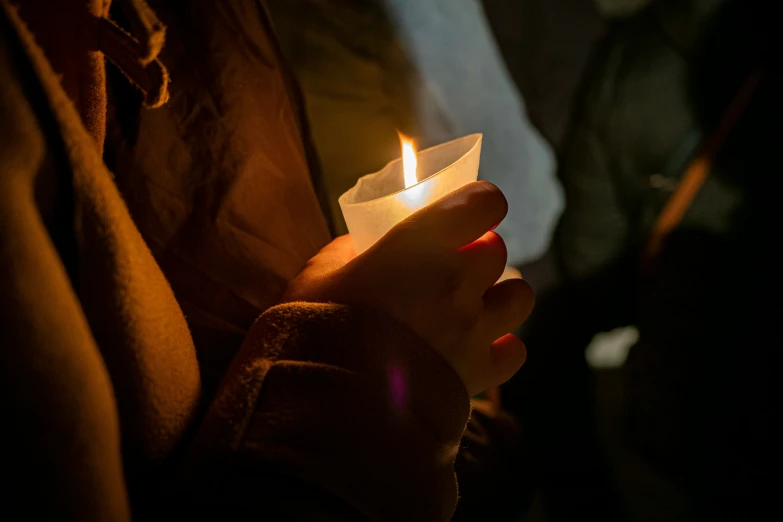 the person is holding the candle in one hand