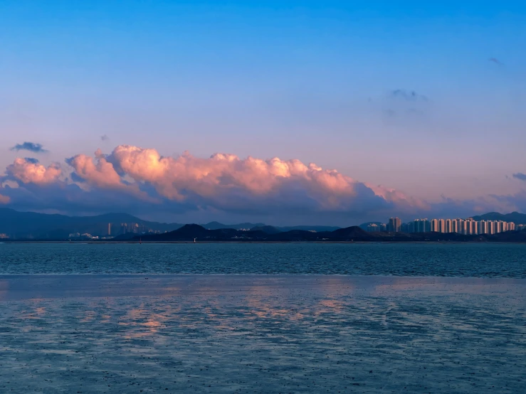 a large cloud hanging over a city under a blue sky