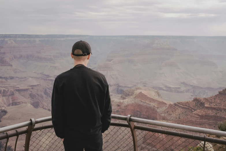 man standing on fence overlooking landscape in outdoor area