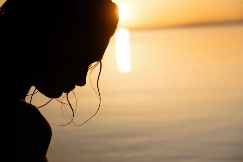 a woman is watching the sunset with her phone