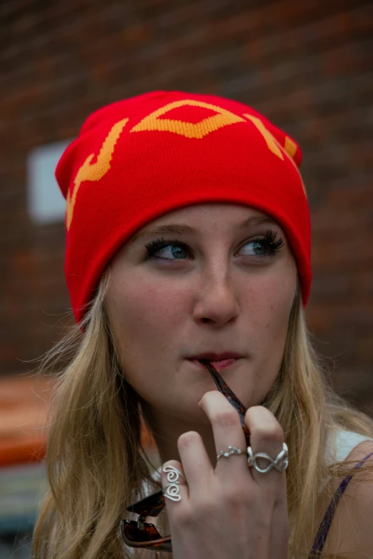 a blonde girl wearing red is smoking her cigarette