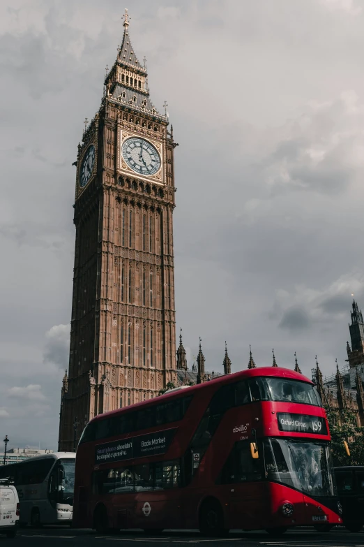 a red double decker bus driving past big ben