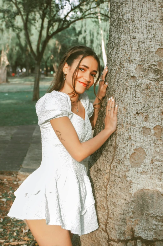 a woman standing near a tree and wearing red lipstick