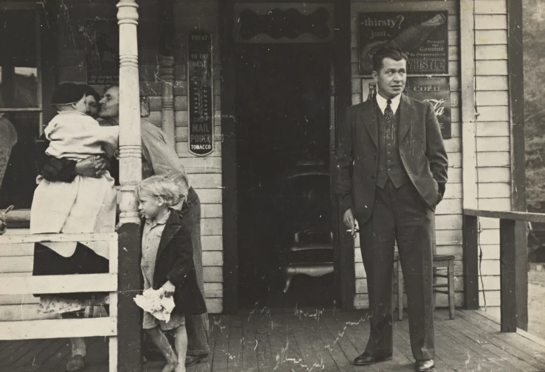 a man wearing a suit standing on a porch with a little girl sitting on a chair