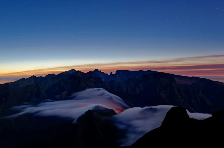 a view of some mountains under a night sky