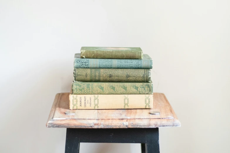 four books are stacked on top of a stool