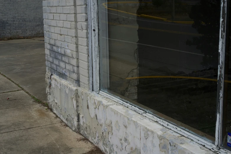 a window sill with some paint peeling off and the reflection in it