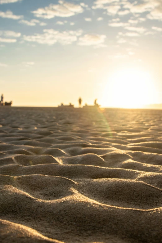 people in the distance on sand with a blue sky