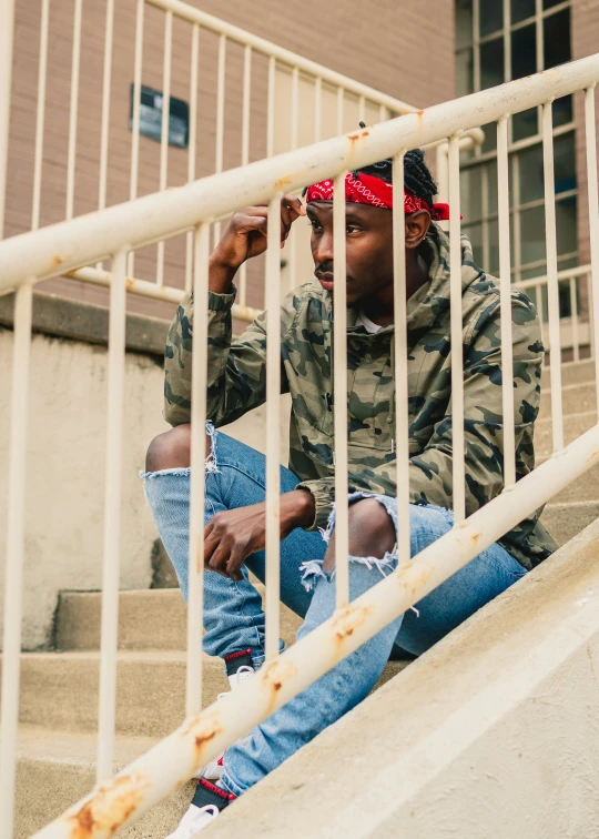 a young man sits on stairs with his foot over his hat