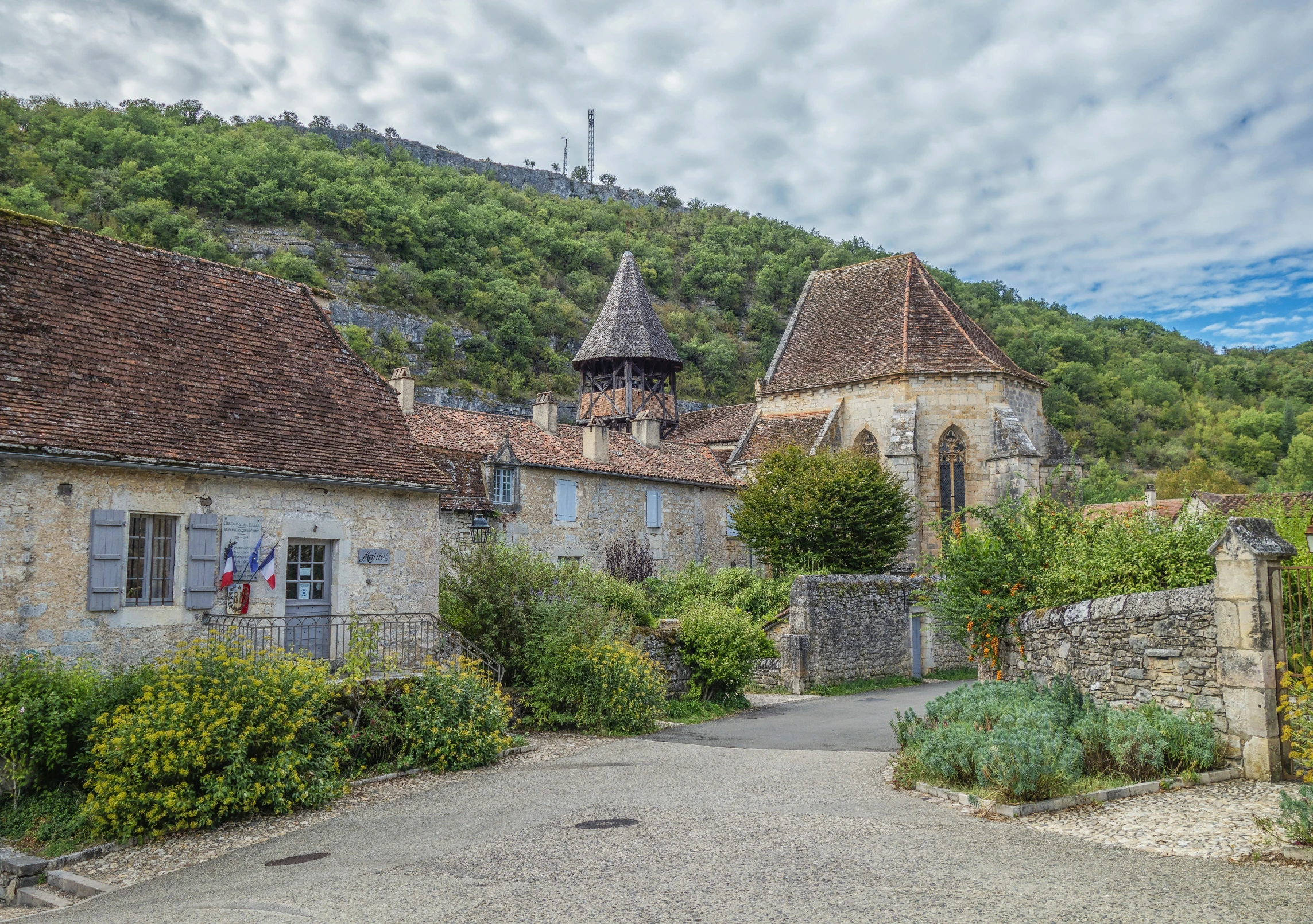 a small stone building in the middle of a lush green hillside