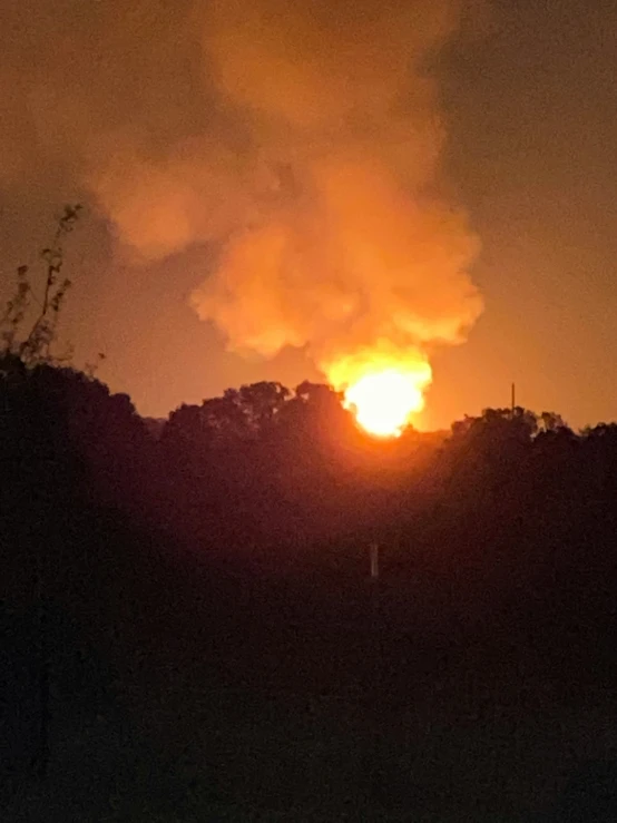 a fireball with smoke and a building in the background