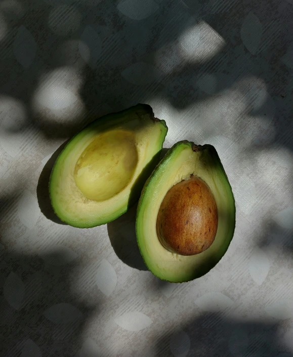 two pieces of avocado are half opened with a small piece cut in half