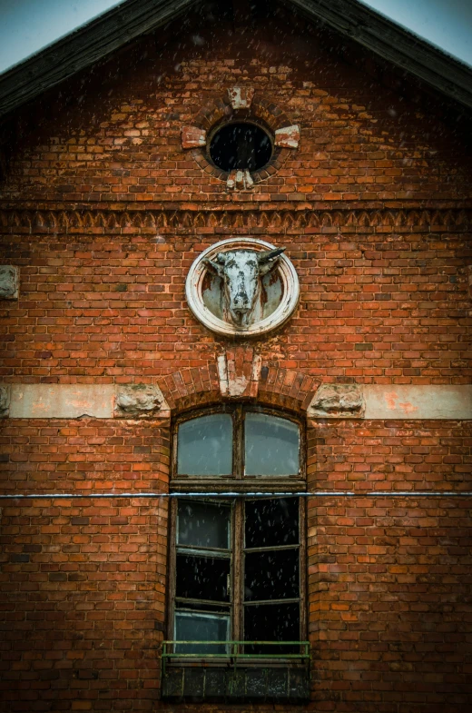 a cow head hanging from the side of a red brick building