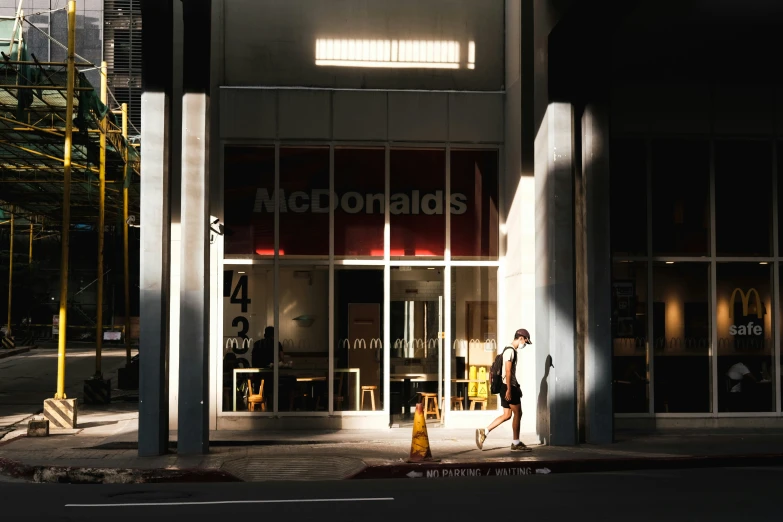 the front of a mcdonalds restaurant with people walking outside