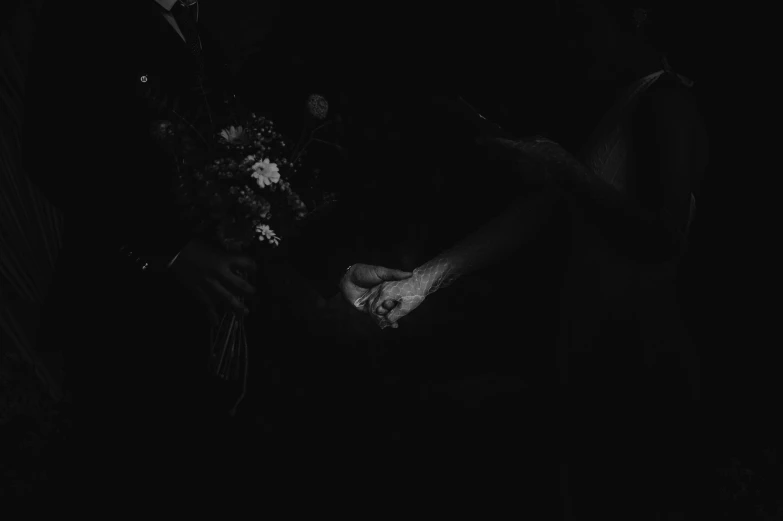a man laying in the dark while holding a bunch of flowers