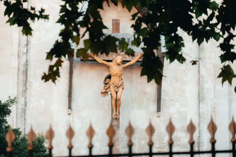 a wooden cross with nches around it behind a metal fence