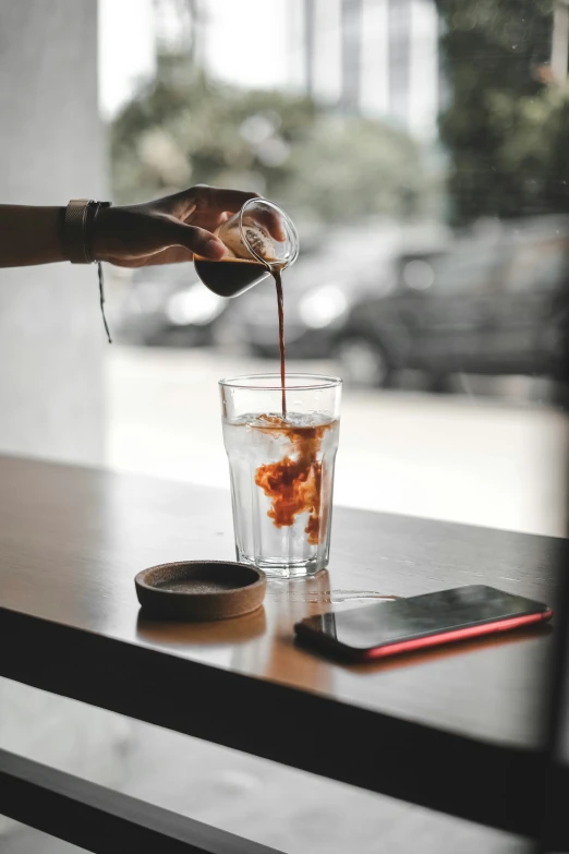 someone is pouring drinks into a glass