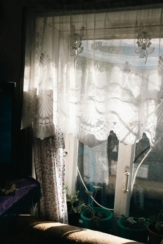 a window covered in white lace next to a window sill