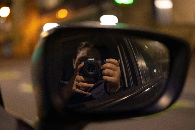 someone taking a selfie in the rear view mirror