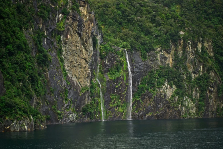 waterfall and boat in the water with mountains in the background