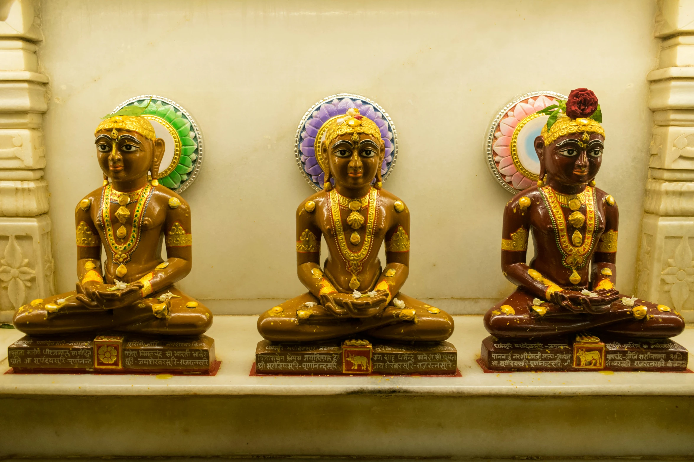 a trio of seated buddhas are displayed near wall