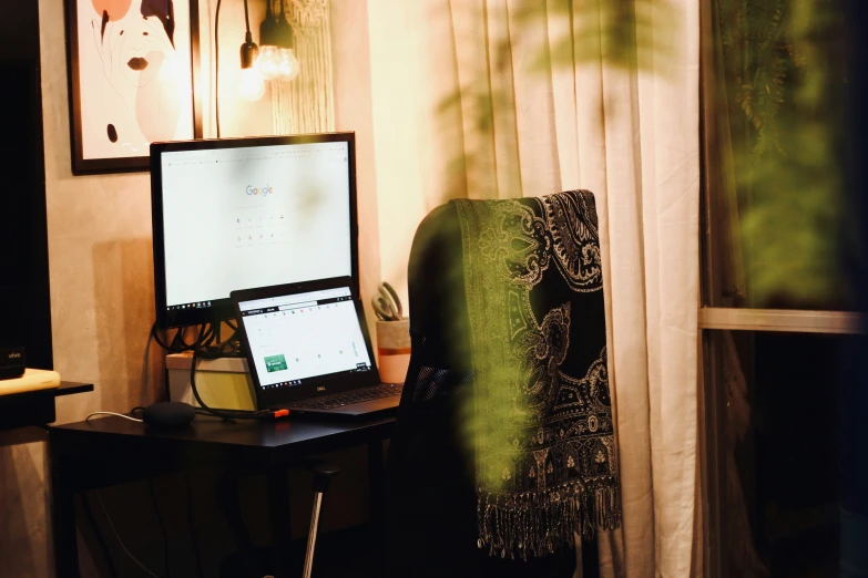 laptop computer sitting on a desk next to a painting