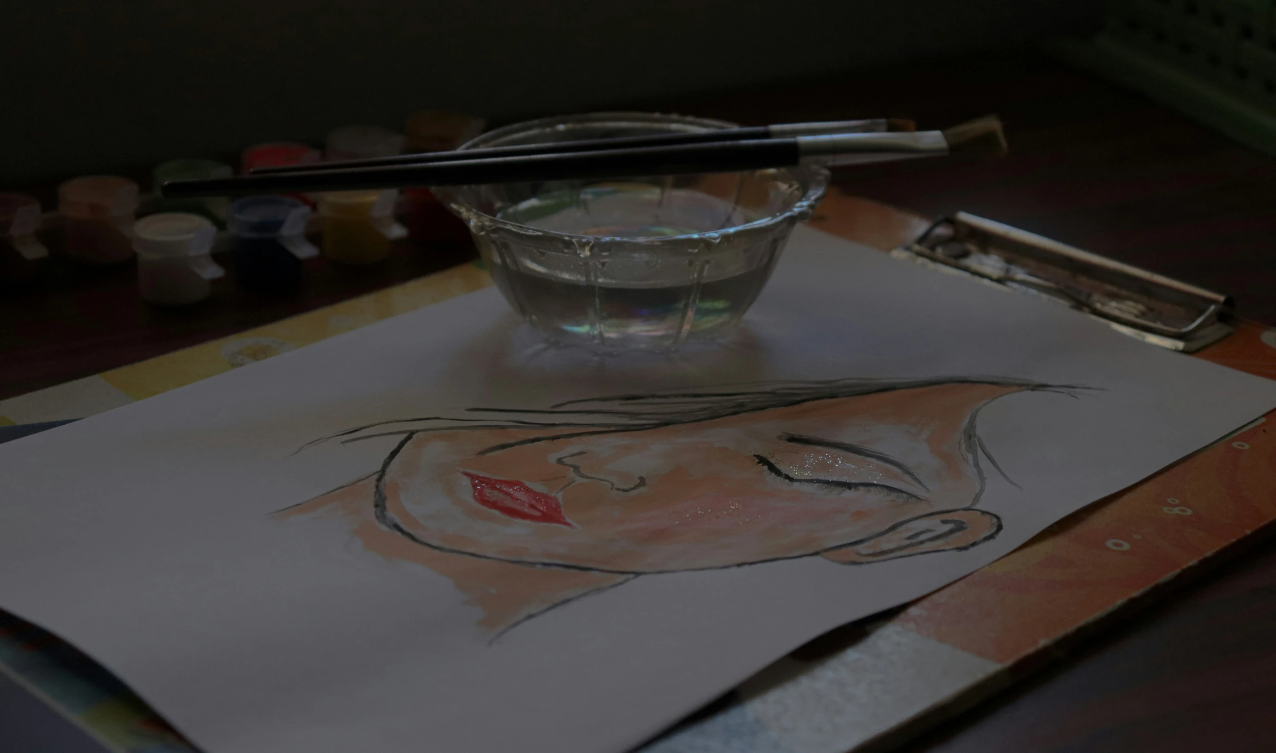 a glass with water in it next to a pencil and drawing on paper