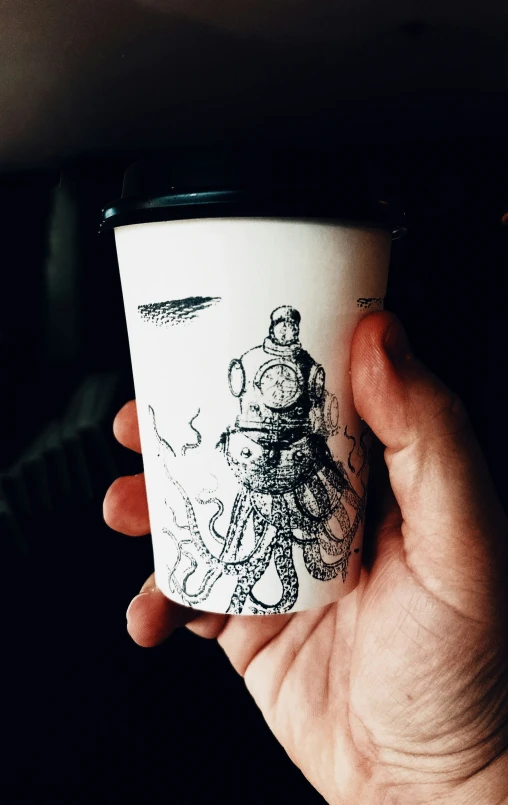 a person holds a coffee cup with drawings on it