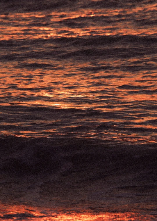 an orange and purple sunset with some water below