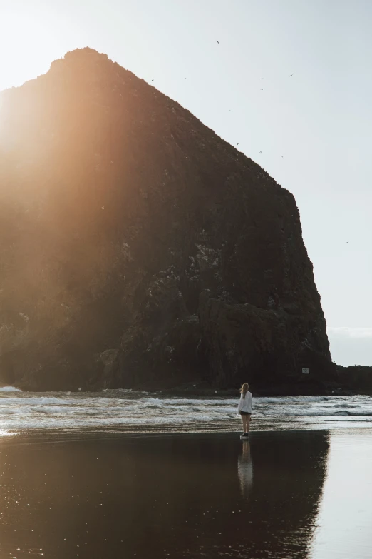 a man standing on the beach with his surfboard