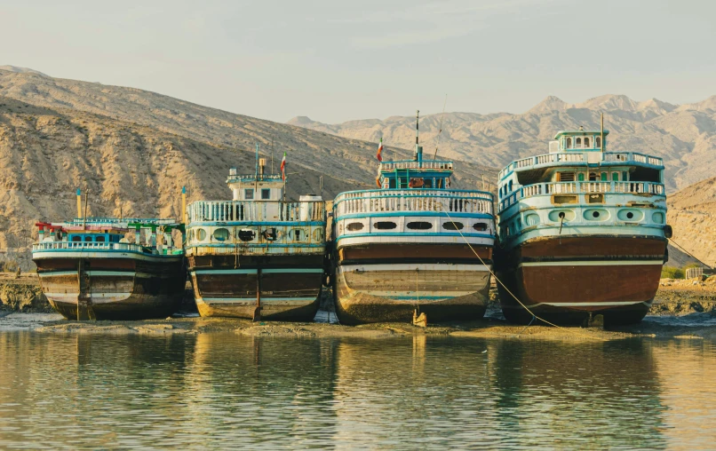 several different boats sit docked along a lake