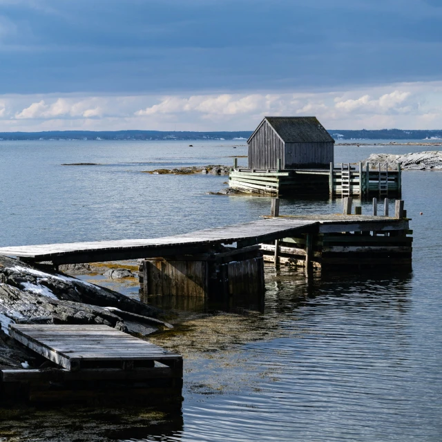 a dock at the lake with a wooden house