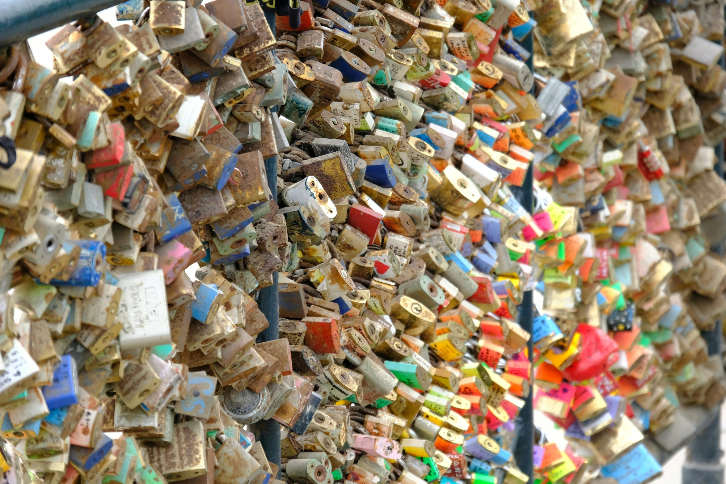 padlocks are on a fence and some are covered with colored wooden beads