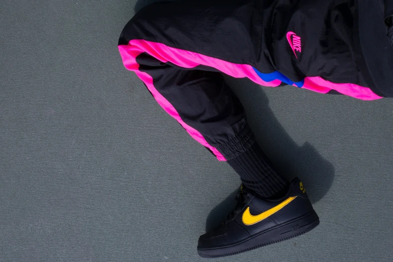 a person in a black nike sneakers and a neon colored pants