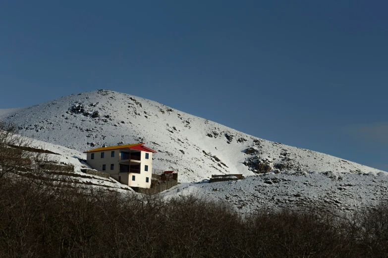 a house in the middle of the mountains covered with snow