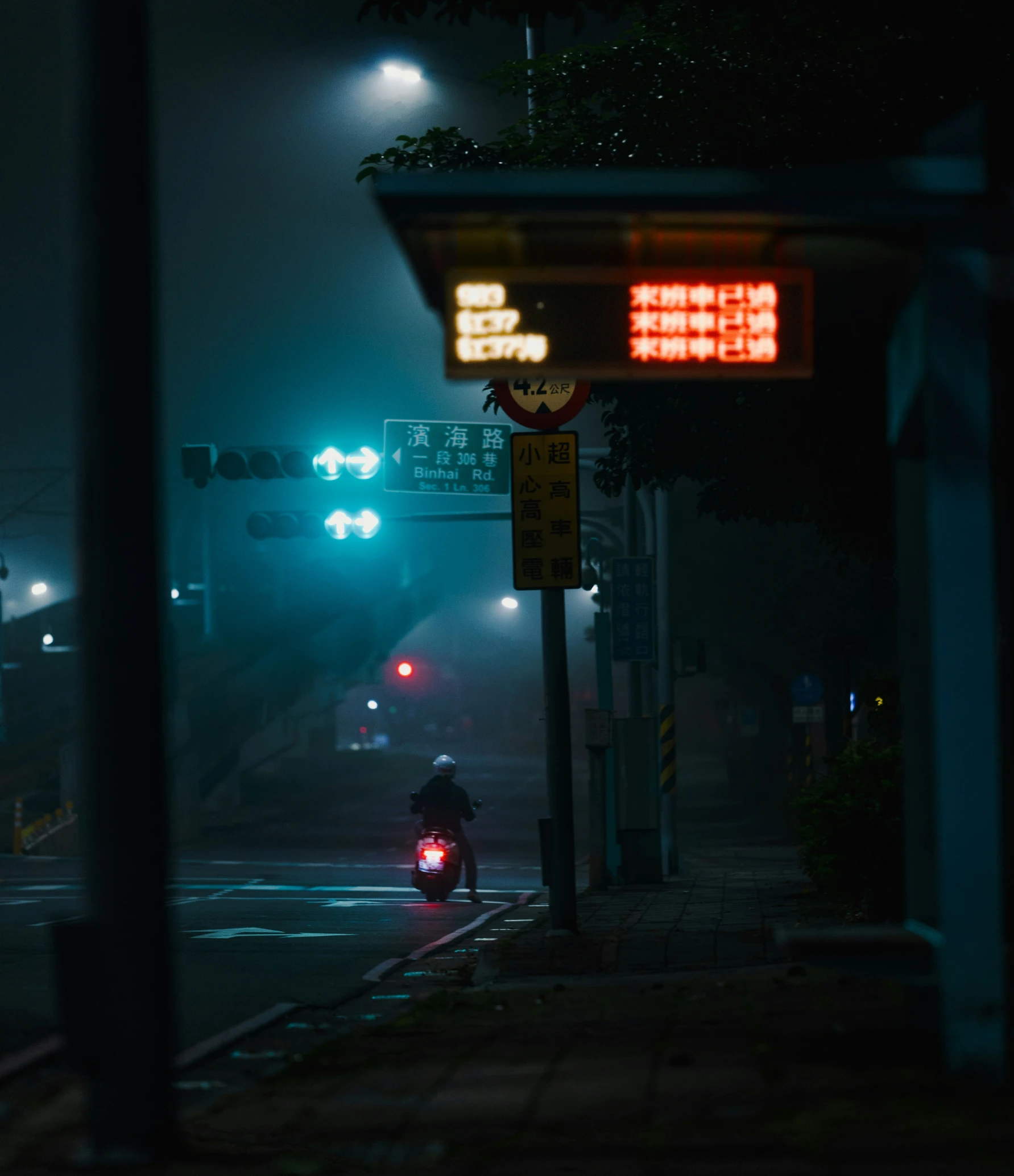 a man riding his motorcycle at night with traffic lights