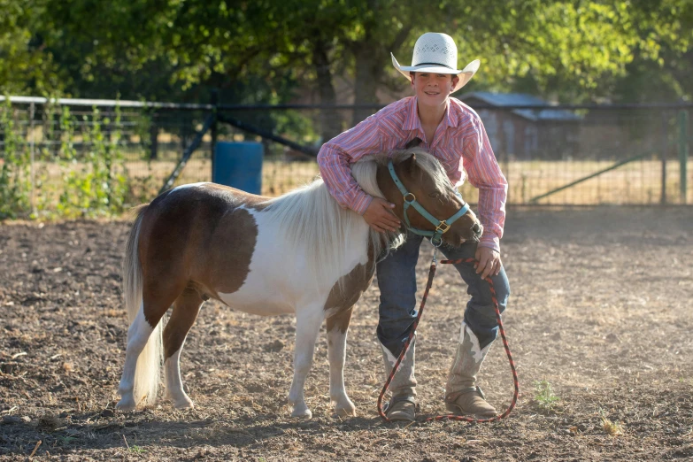 man in cowboy hat holding the reins of his horse