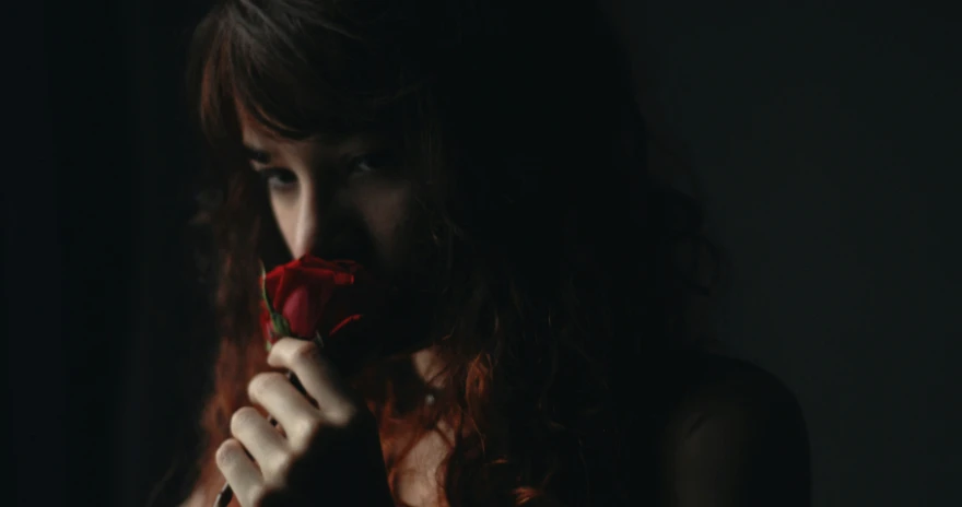 a girl that is holding a rose up in the air