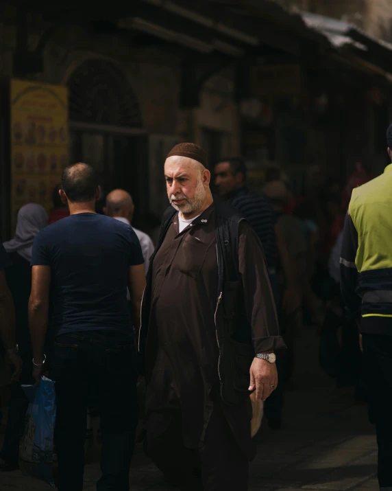 a man with beard and dress walking in a crowded street