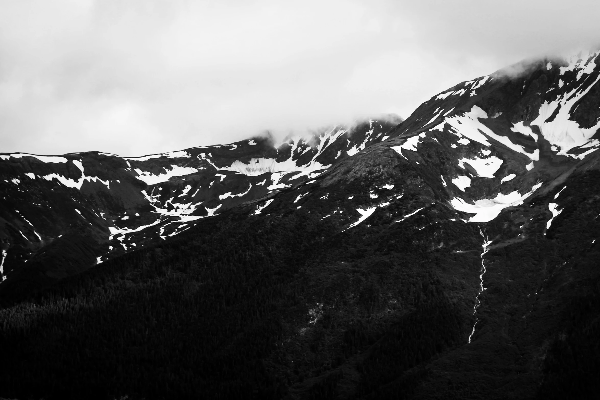 a picture of a mountain range with clouds overhead