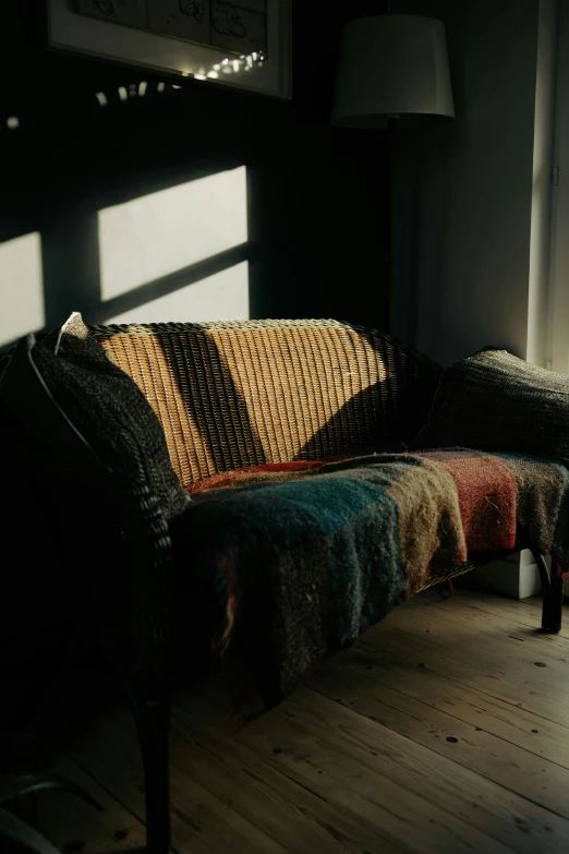 a plaid couch is sitting in the dark by a window