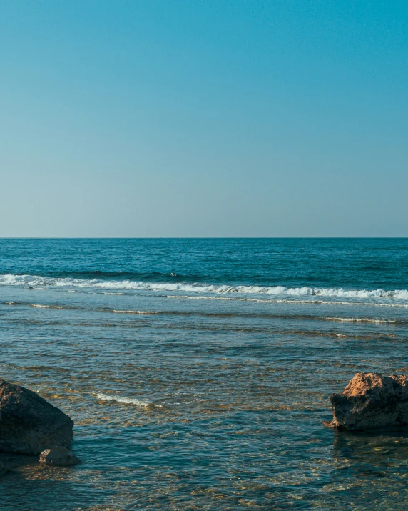 a man walking towards the ocean carrying his surfboard