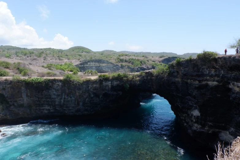 a cave on the edge of a large cliff next to water