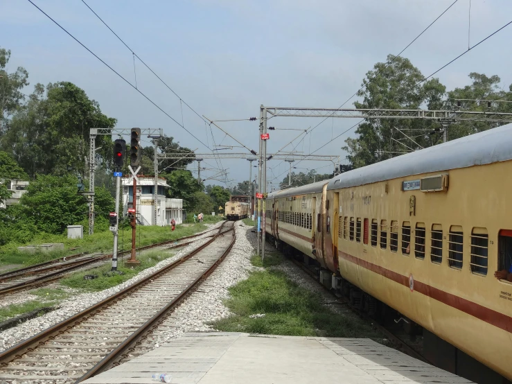 the yellow train is stopped at the side of the tracks