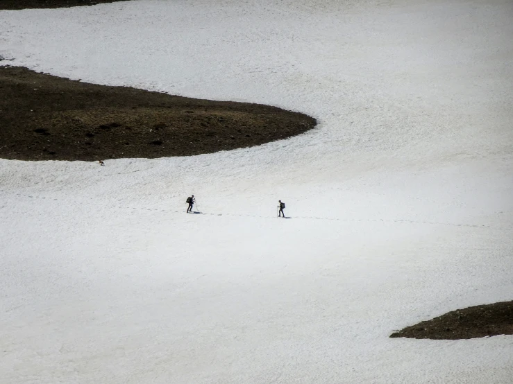 two people are walking up a hill side in the snow