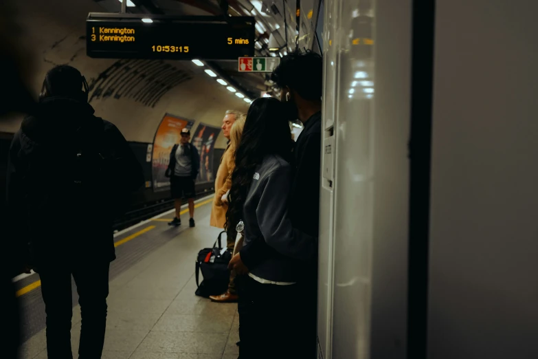 passengers standing on a subway platform next to an open door